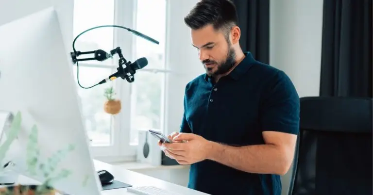 person on their phone sitting at a desk with recording equipment