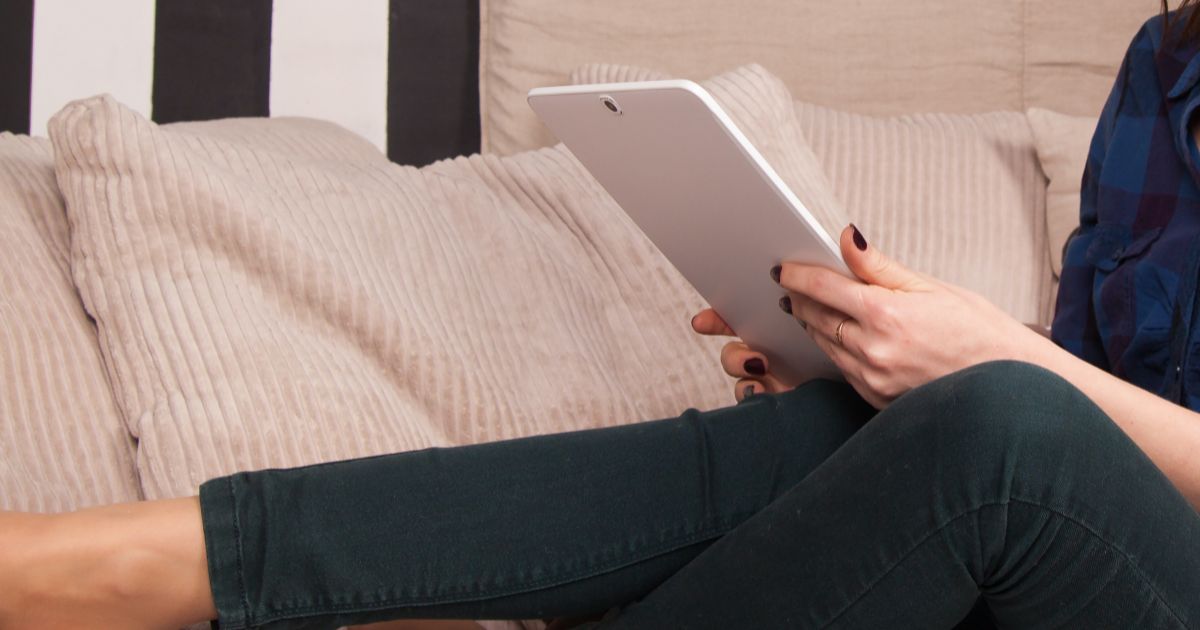 person on a couch looking at their tablet