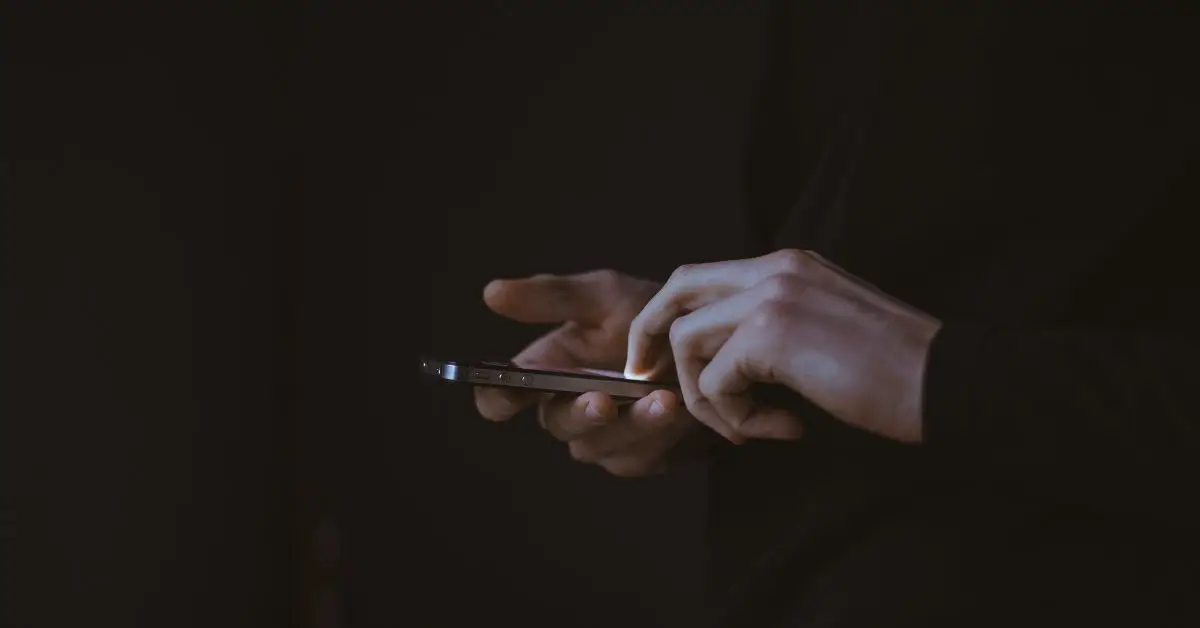 person holding a smartphone in a dark room