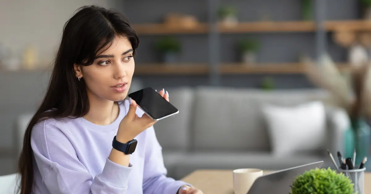 woman sitting down holding her phone in her right hand and speaking into it