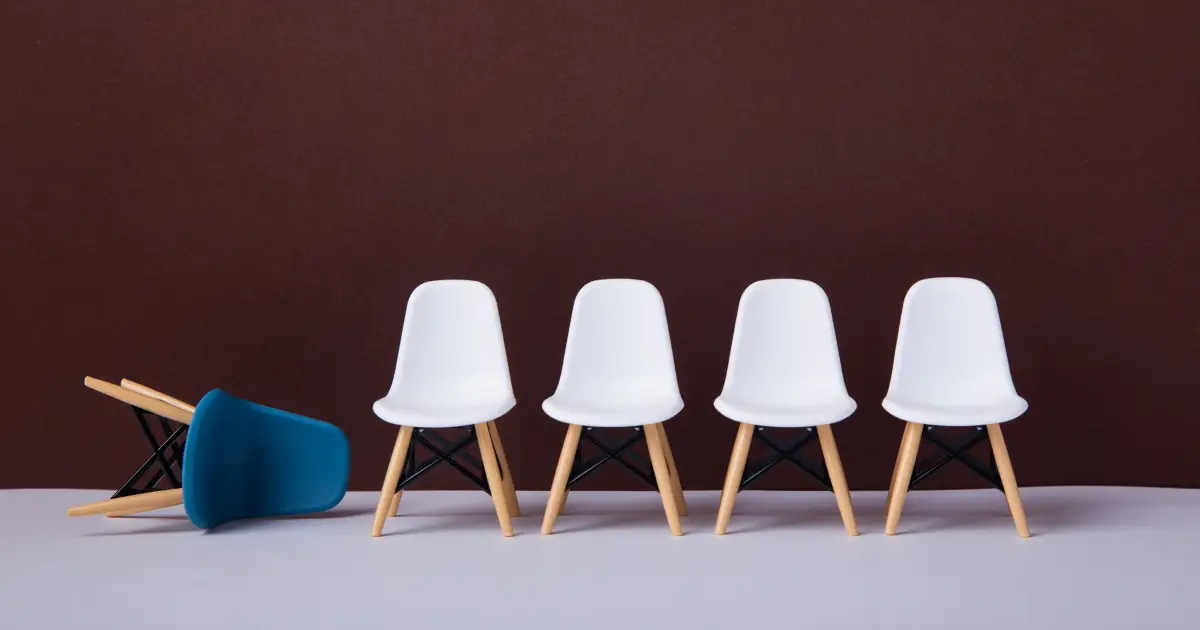 row-of-white-chairs-and-a-blue-one-falling-down